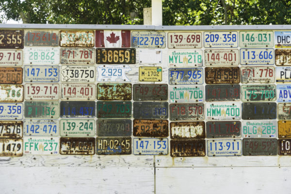 A wall of old license plates with numbers on them.