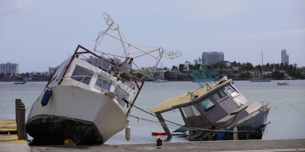 A boat is broken up and laying on the ground.